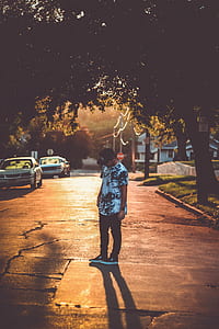 man standing on road between trees thumbnail