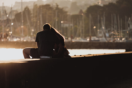 man and woman sitting on concrete surface during daytime thumbnail