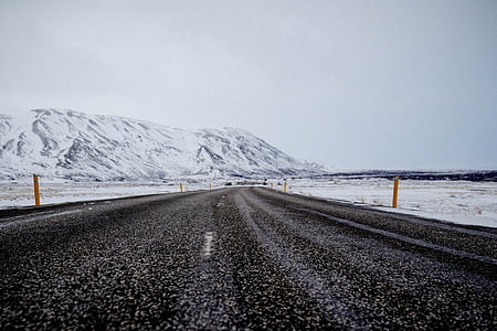 asphalt road beside snow capped mountain during daytime thumbnail