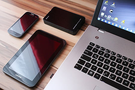 gray laptop computer beside tablet computer and smartphone on brown wooden surface thumbnail