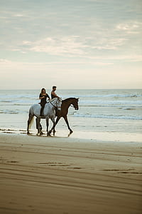man and woman riding on a horse to walk on shore thumbnail