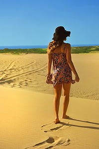 woman wearing bucket hat standing on sand thumbnail