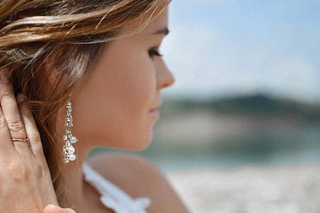 shallow focus photography of woman wearing white top and dangle earring thumbnail