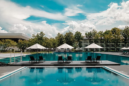 Black Outdoor Lounge Chair in Between Blue Swimming Pool Under White Cloudy Blue Sky thumbnail