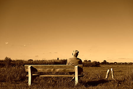 grayscale photography of man sitting on bench thumbnail