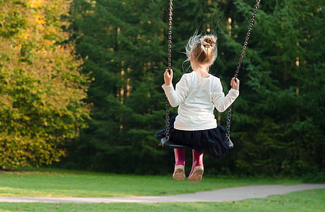 girl in white sweater and black skirt sitting on black swing thumbnail