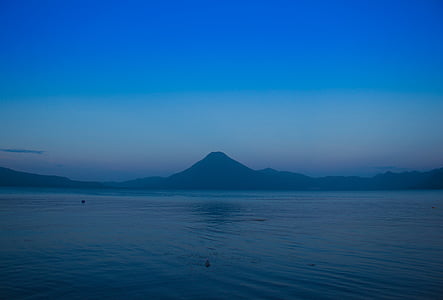 rippling body of water beside mountains at sunset thumbnail