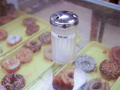 Sugar in a glass container with donuts underneath it. thumbnail