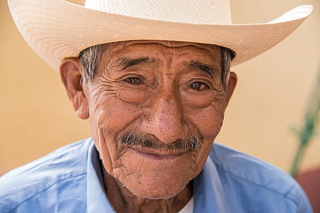 man wearing blue collared top and white woven hat thumbnail