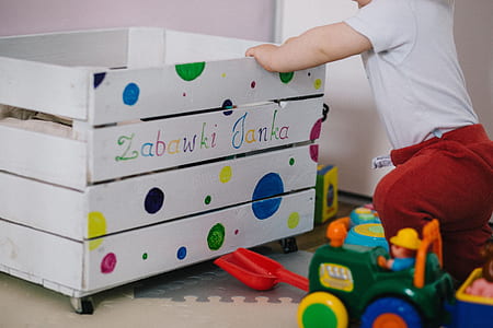 toddler holding on to white wooden toy storage box thumbnail