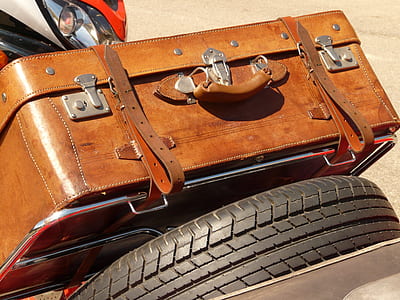 brown leather suitcase beside black auto tire thumbnail