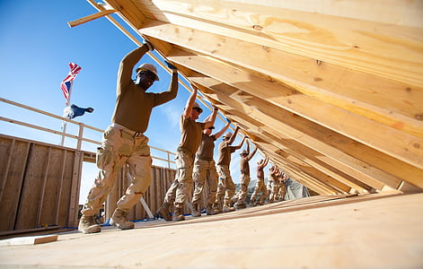 group of men pushing beige wooden wall during daytime thumbnail