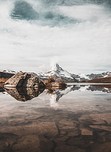 body of water across mountain covered with snow during daytime thumbnail