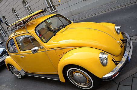 yellow Volkswagen Beetle couple on roadway near gray building thumbnail