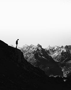 grayscale photography of a man standing at the cliff thumbnail