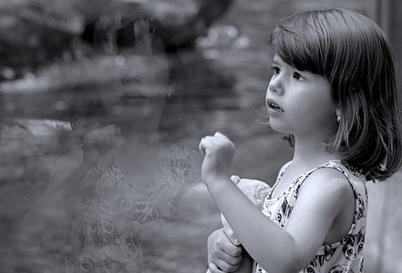 grayscale photo of girl standing next to clear glass panel thumbnail