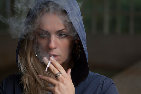 woman wearing blue hooded jacket while puffing a single cigarette thumbnail