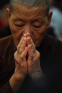 praying man wearing brown top in close-up photography thumbnail