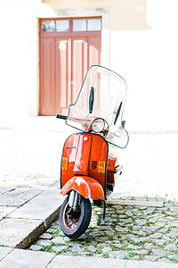 orange motor scooter parked beside bricked sidewalk thumbnail