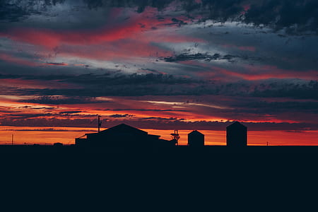 silhouette photography of house and two silos during golden hour thumbnail