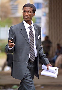 person wearing gray blazer holding white printer paper thumbnail