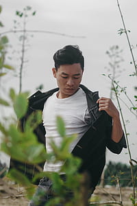 man opening black jacket near green grass at daytime thumbnail