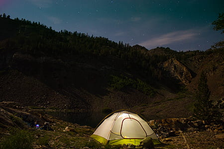 white and green tent distance with mountains and trees thumbnail