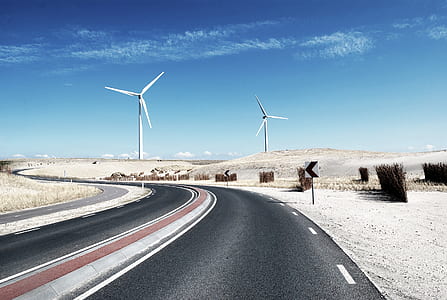 gray curved road beside arrow left signage under white cloud blue skies thumbnail