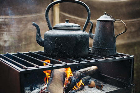fire burning under black kettle on metal grill thumbnail
