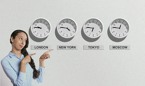 selective focus photography of woman pointing four analog wall clocks thumbnail