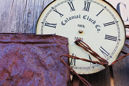 round white Colonial Clock Co. analog clock on brown wooden surface thumbnail