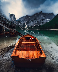 brown wooden boat on seashore in front of blue body of water under nimbus clouds at daytime thumbnail