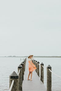 woman in orange sleeveless dress standing on dock thumbnail