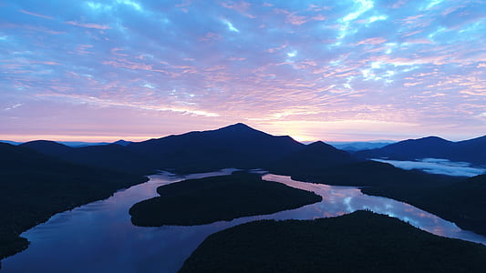 aerial photo of island surrounded by body of water and mountain under blue sky at daytime thumbnail