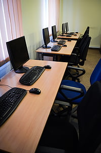 five black flat screen computer monitors on brown wooden desks thumbnail