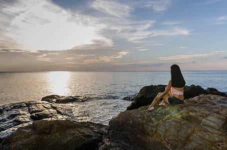 woman sitting near rock formation in front of sea thumbnail