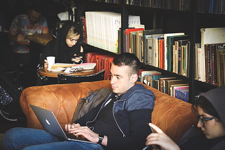 man sitting brown tufted couch in front silver MacBook thumbnail
