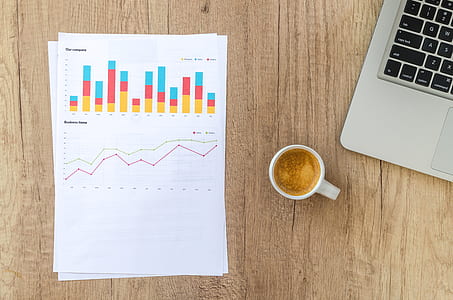 bar and line graph printed on white printer paper beside white ceramic coffee mug filled with coffee thumbnail