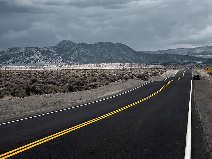 gray asphalt road in between gray grass field