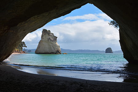 cave near seashore under blue and white sky thumbnail
