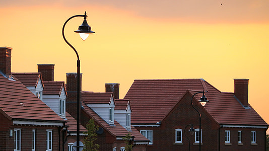 black street lamps beside brown concrete buildings under orange sunset thumbnail