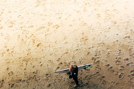 man carrying surfboard in top view photography thumbnail