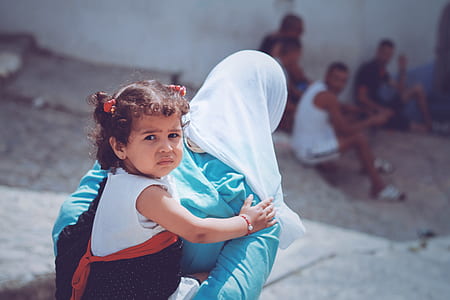 woman carrying girl during daytime thumbnail