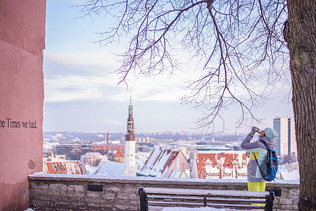 man standing beside wooden bench and tree thumbnail
