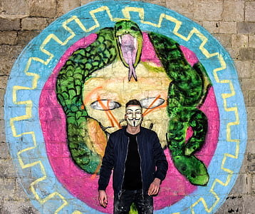 man wearing mask standing near wall thumbnail