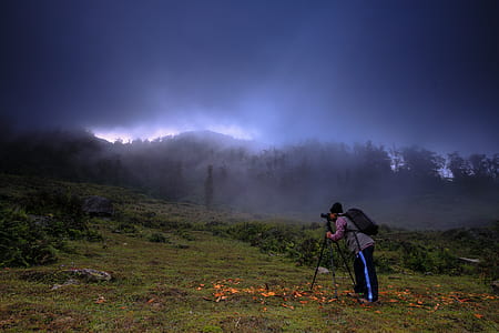 man taking photo of foggy forest during daytime thumbnail