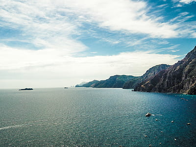 mountain near sea under blue sky thumbnail