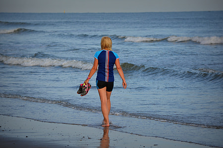 woman walking beside body of water during daytime thumbnail