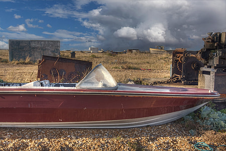 An old abandoned speed boat sits on the shingle beach at Dungeness, Kent, England thumbnail