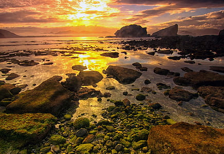 body of water with rocks during golden hour photography thumbnail